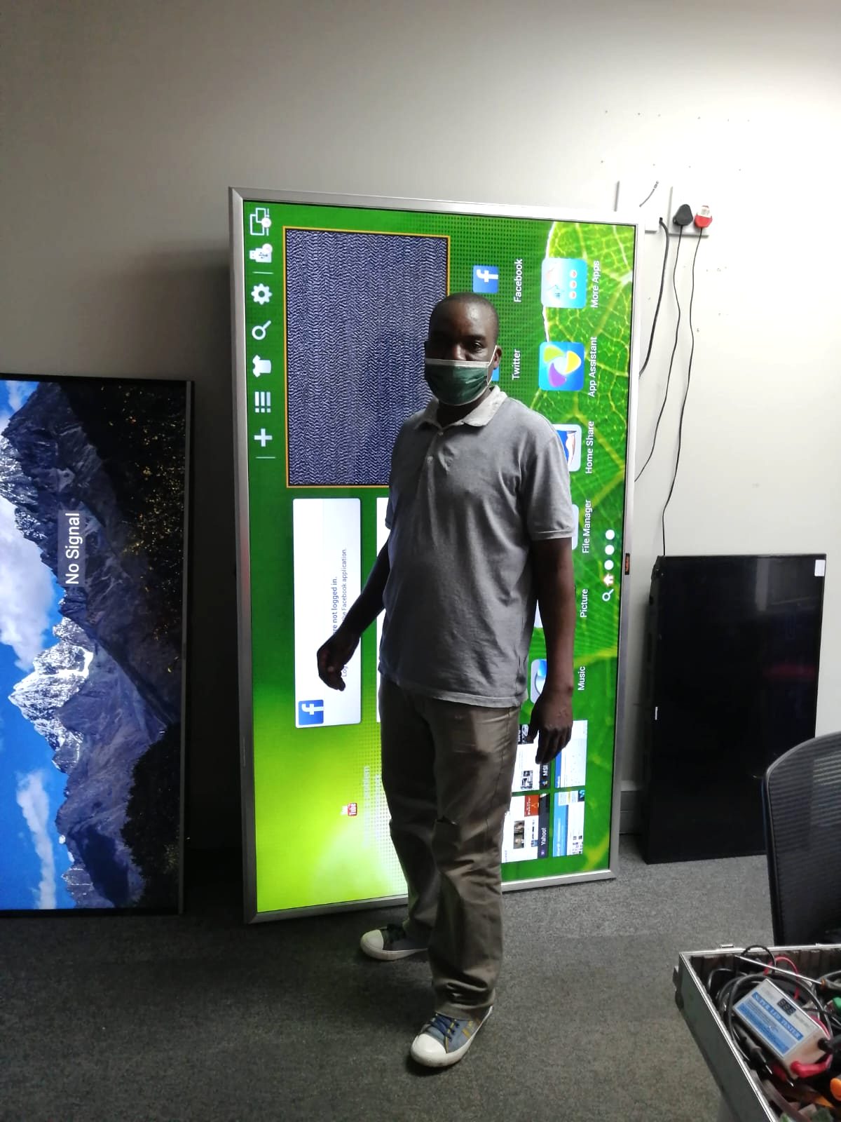 Technician standing beside a large repaired television display