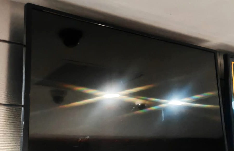 Dark commercial display screen mounted beside working screens