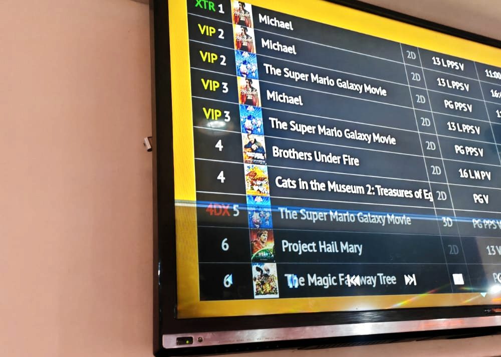 Wall-mounted schedule display screen showing a listings grid